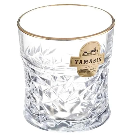 Clear glass tumbler with gold rim on a white background