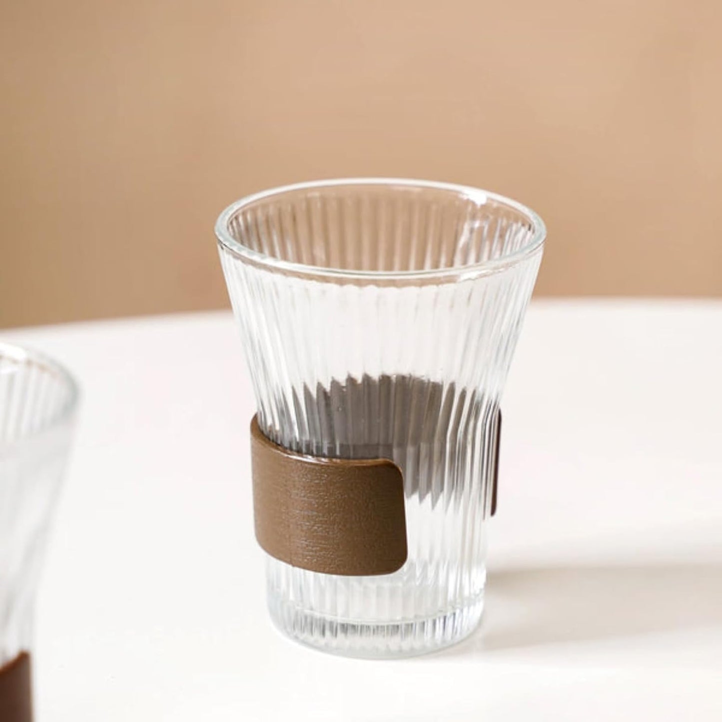 Clear glass with a brown strap on a beige background