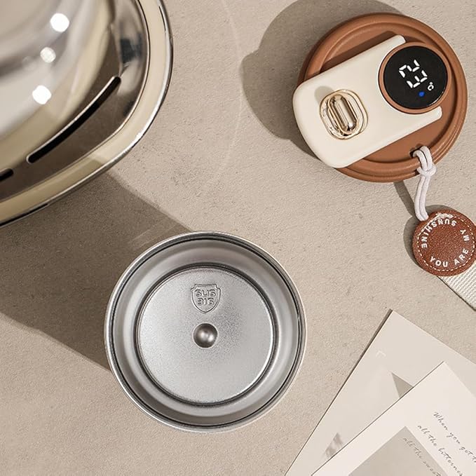 Metallic lid on a beige surface with a digital thermometer and small round object in the background.