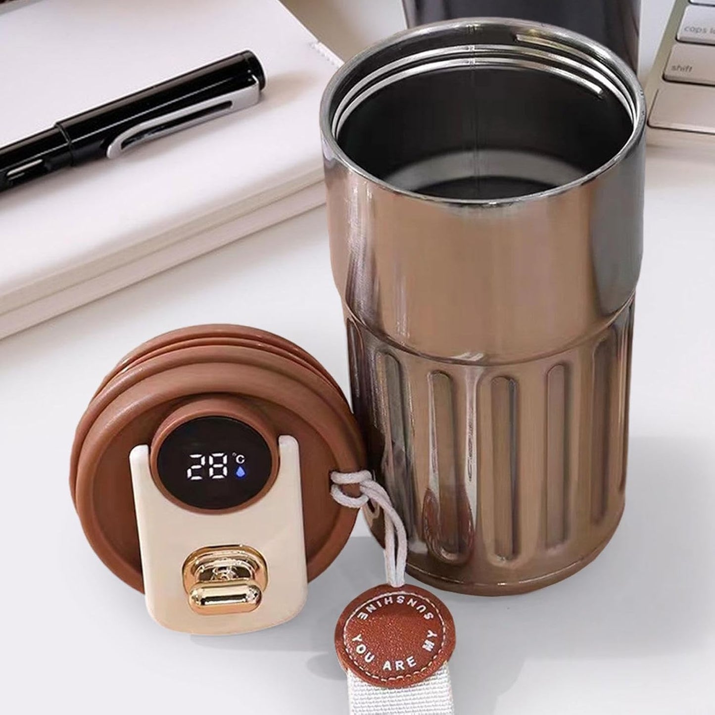 Brown insulated mug with digital temperature display and USB charging port on a white surface.