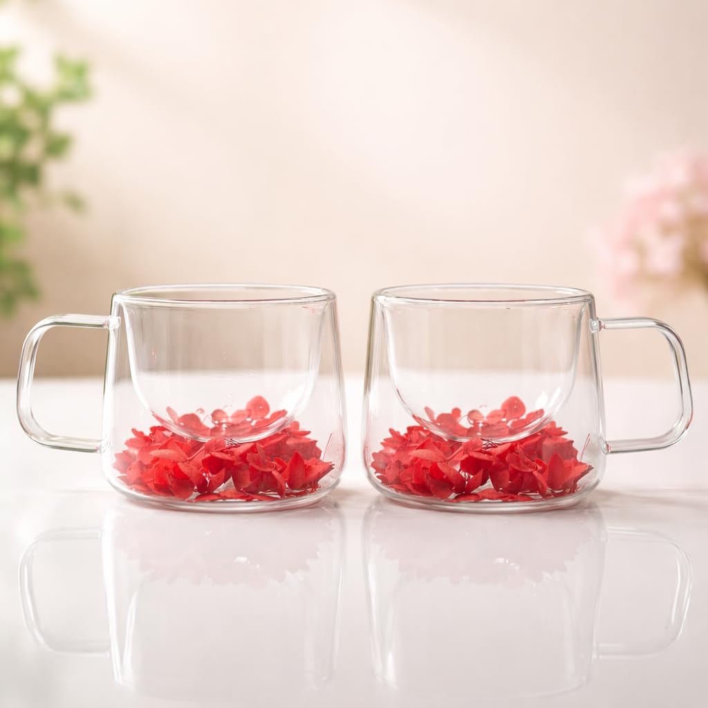 Two clear glass mugs with red flowers on a light surface.