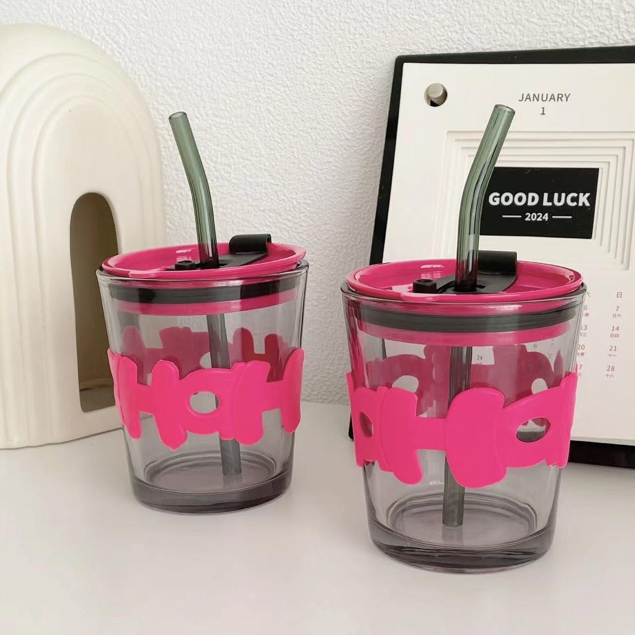 Two clear tumblers with pink 'Hot' and 'Cold' labels and black straws on a white surface.