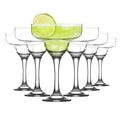 Set of eight clear martini glasses with lime wedges on a white background