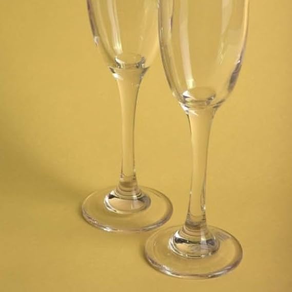 Two clear champagne flutes on a yellow background