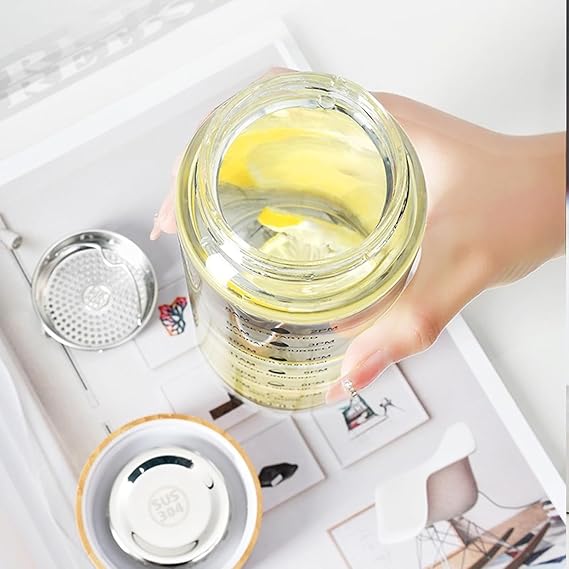 Hand holding a clear jar with a yellow substance on a white surface