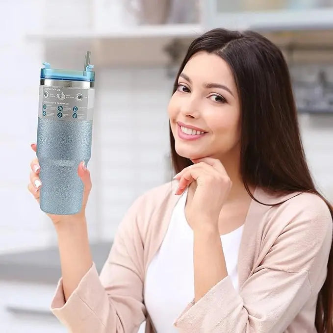 Woman holding a blue glittery tumbler with a straw in a kitchen setting