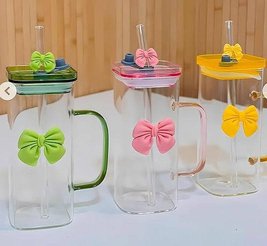 Three glass mugs with colorful bow-shaped lids on a wooden surface.