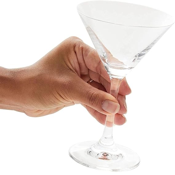Hand holding a clear martini glass against a white background