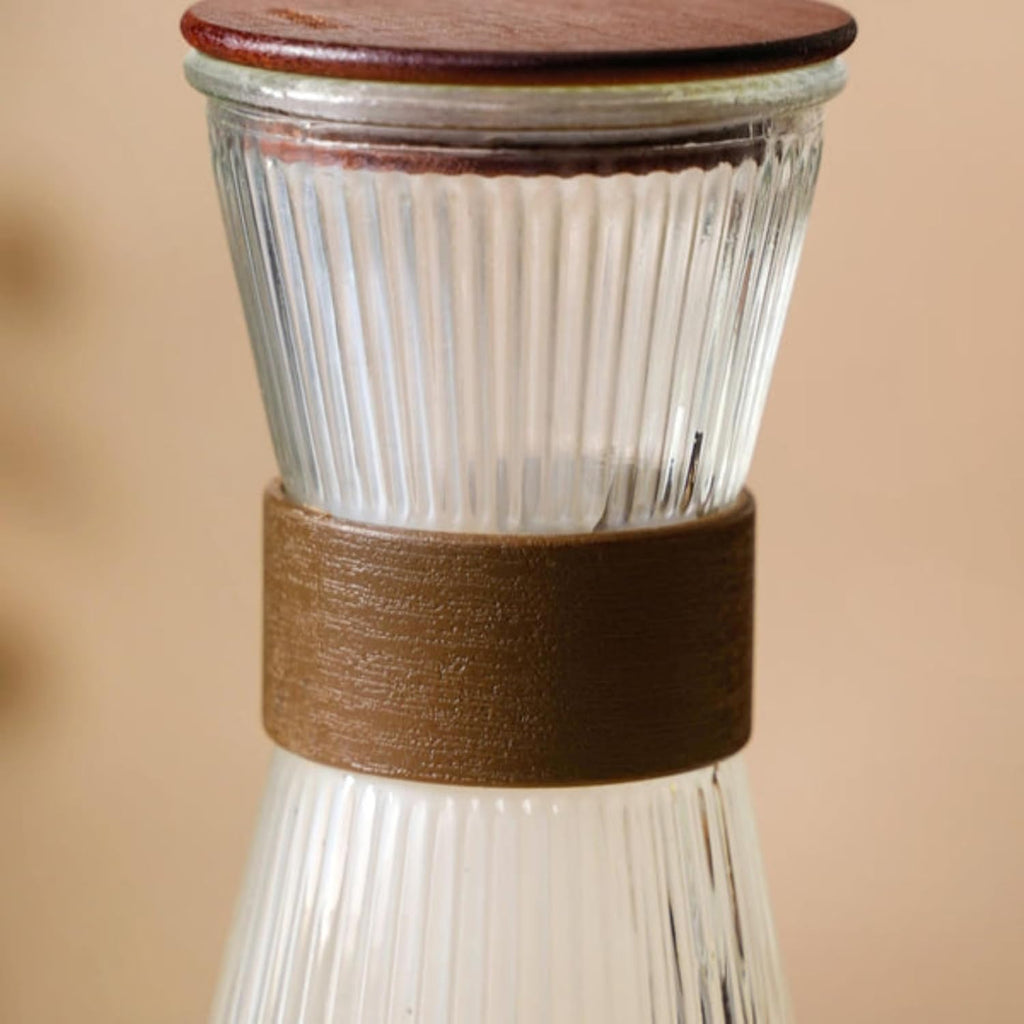 Glass jar with wooden lid and brown leather strap on a beige background
