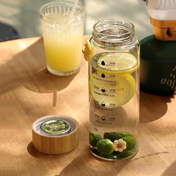 Glass water bottle with lemon design and time markers on a wooden table.