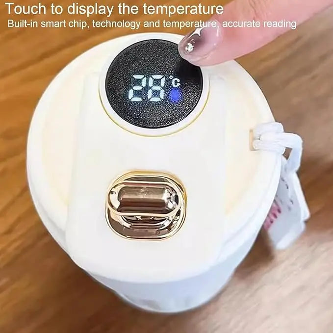 Digital temperature display on a white device with a hand pressing the button, set on a wooden surface.