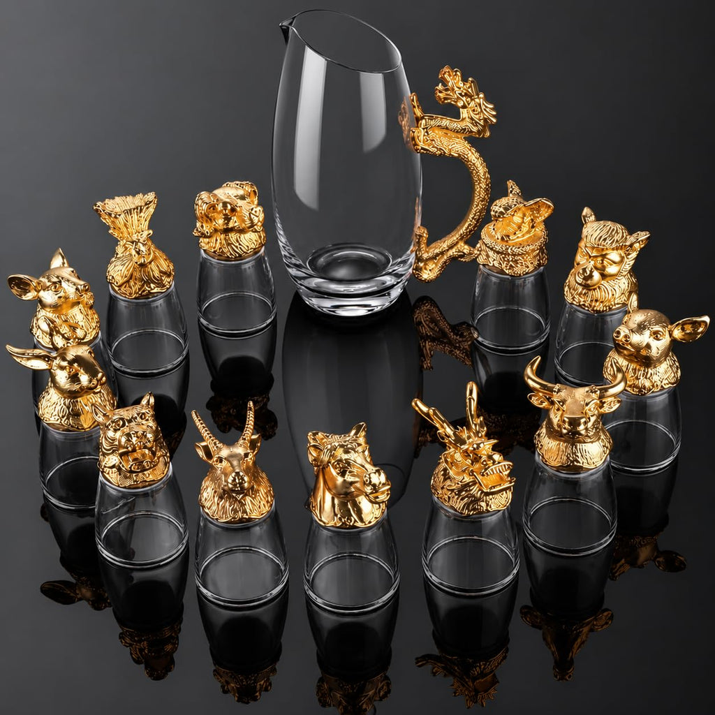 A set of clear glass shot glasses with ornate gold animal and dragon-shaped metal caps, arranged around a tall clear glass pitcher on a glossy black reflective surface.