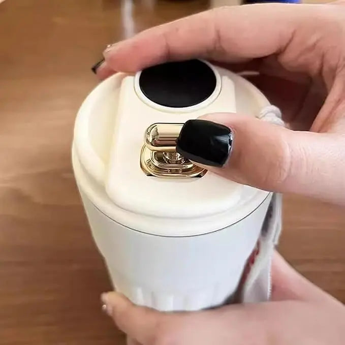 Hand holding a white electronic device with a black button on a wooden surface