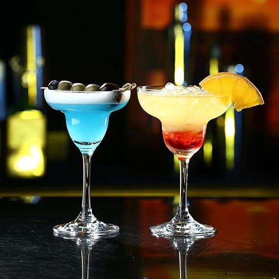 Two colorful cocktails in martini glasses with a blurred bar background