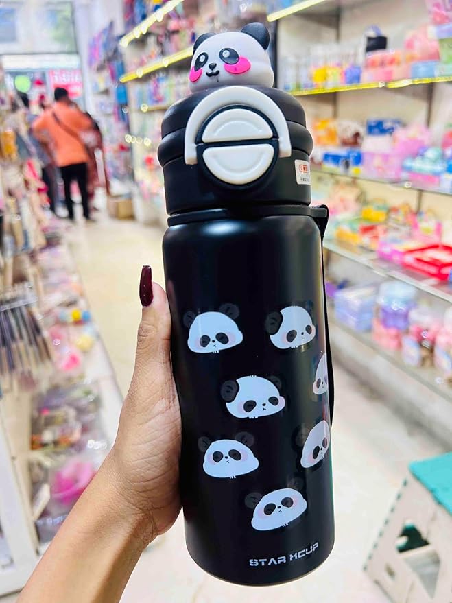 Black water bottle with panda designs held in a hand, with a store in the background