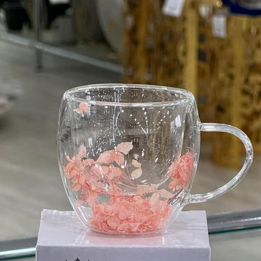 Clear glass mug with pink floral design on a white stand