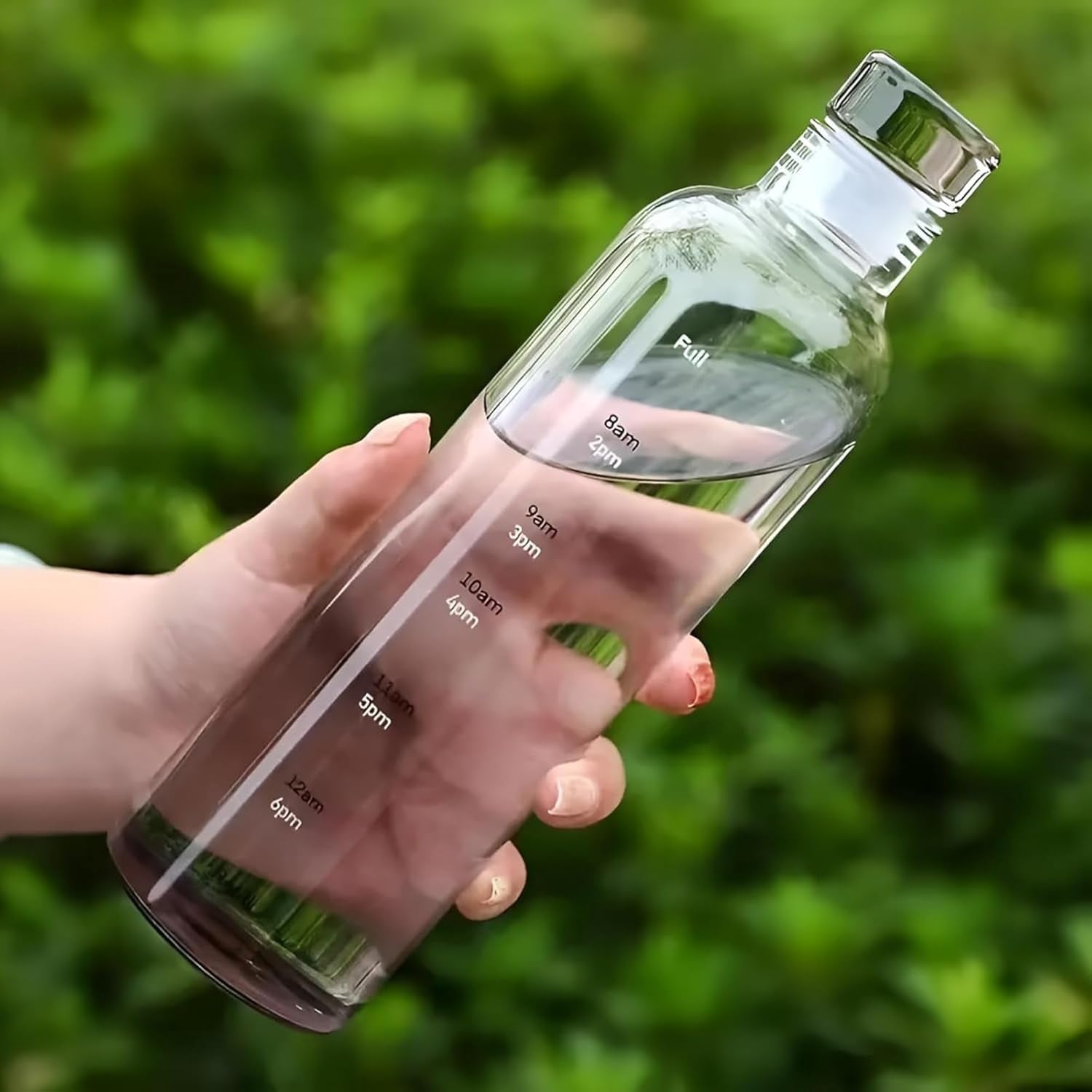 Clear water bottle with measurement markings held by a hand against a green blurred background