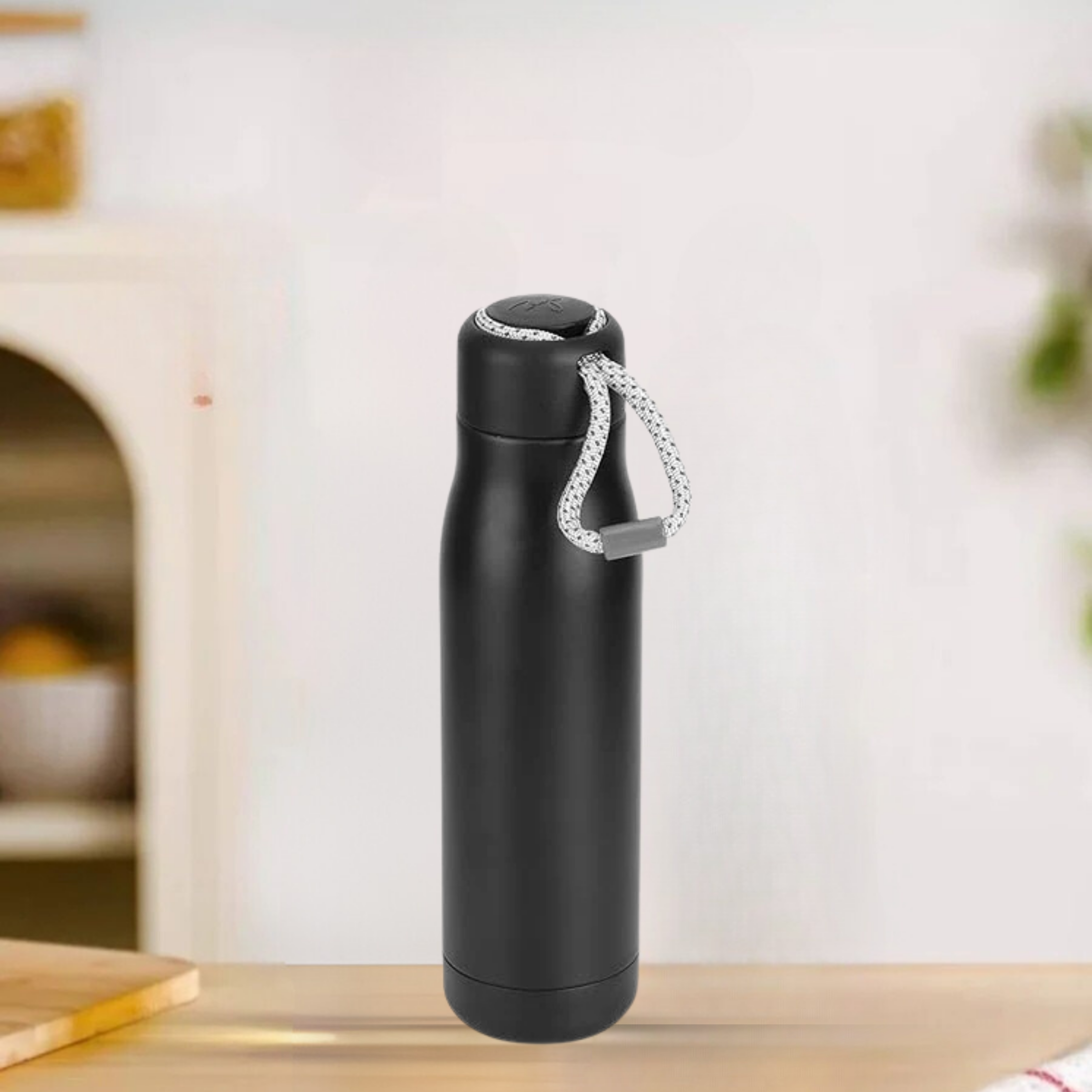 Black insulated bottle with a rope handle on a wooden surface.